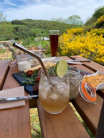 Boisson fraîche au citron vert sur une table de pique-nique, devant des buissons jaunes en fleurs