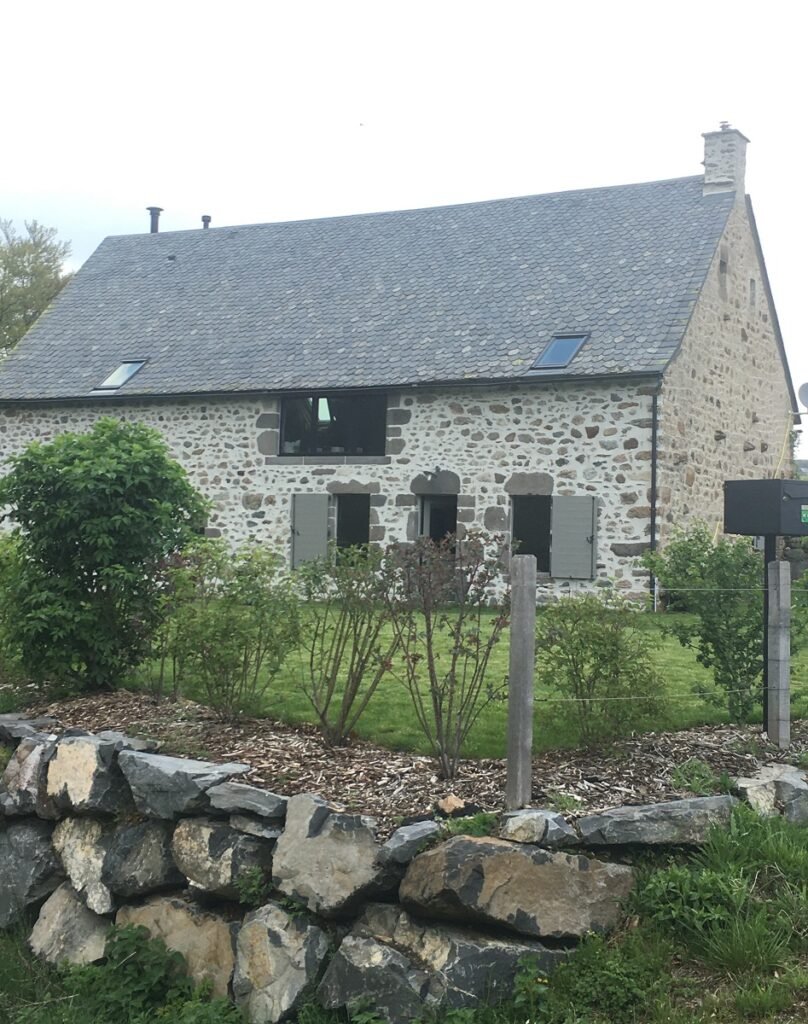 Die Steinfassade von La Grange de L’Abille, ihr Schieferdach und ihr von einer Steinmauer gesäumter Garten