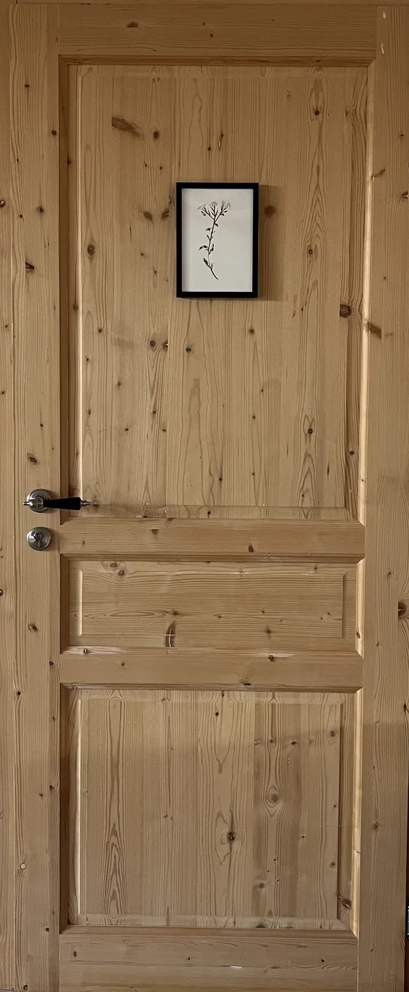 La porte en bois de la chambre Achillée, ornée d'un petit cadre botanique