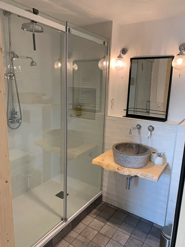 Salle de bain de la chambre Bruyère : douche vitrée et vasque en pierre sur un plan en bois