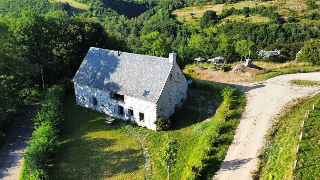 La Grange de L'Abille seen from the sky, surrounded by meadows and forests in the Cantal